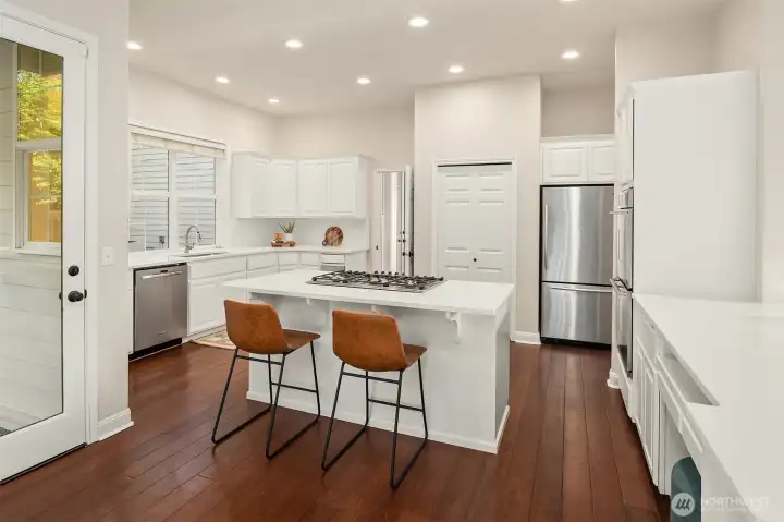 Stainless steel appliances, quartz slab counters, and a freshly painted kitchen.