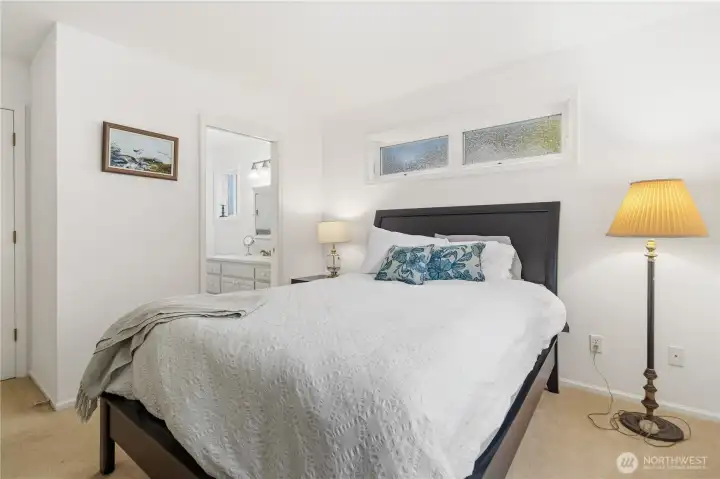 Primary bathroom is just visible beyond the bed.