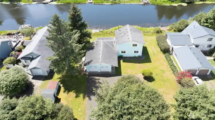 Aerial view of this spacious waterfront property with private dock access, a large lot, and a 2-car garage, all set along the canal.