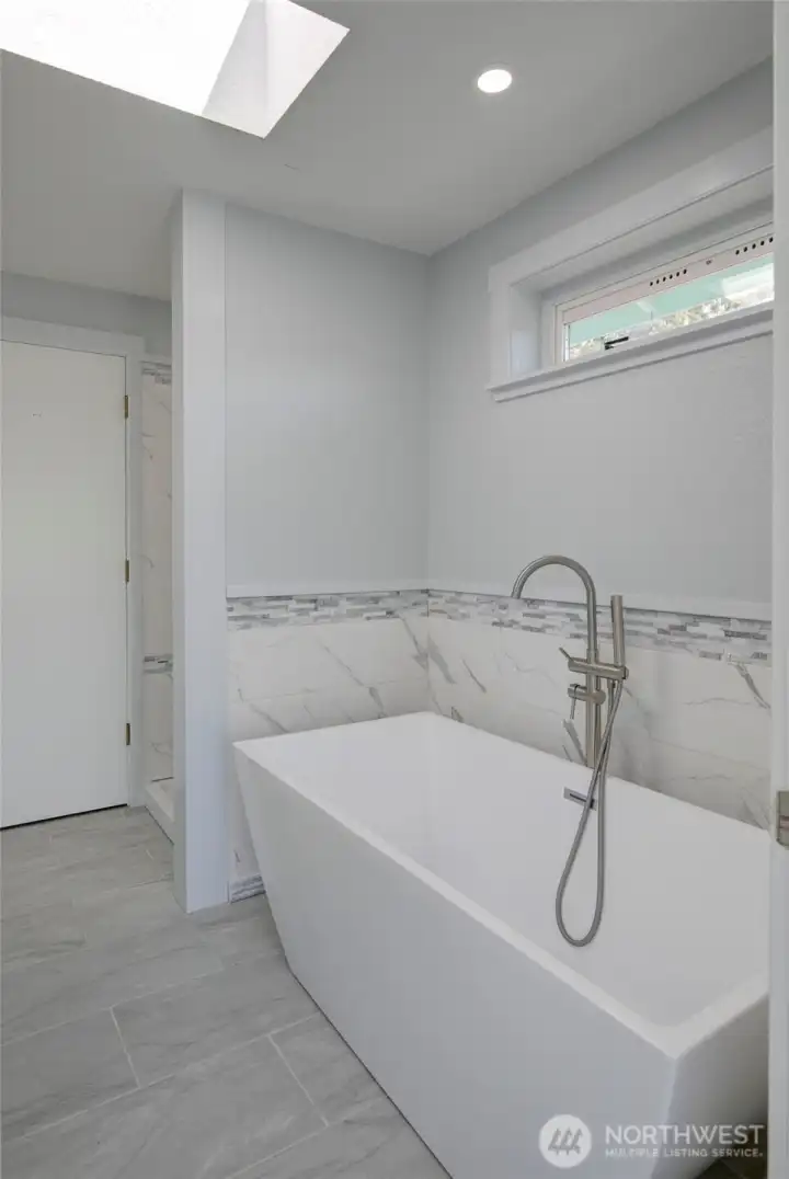 Light-filled primary bathroom with a soaking tub and separate walk-in shower—designed for both relaxation and everyday ease.