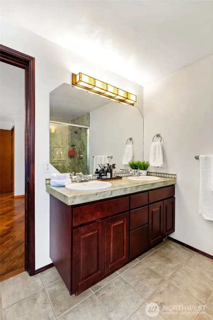 Dual sink vanity and tile walk in shower in the primary bathroom.