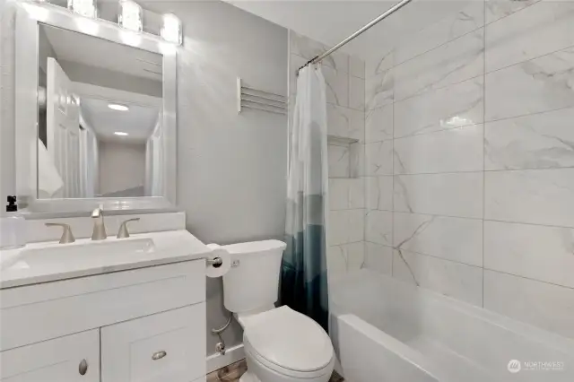 Upstairs bathroom with new vanity, mirror, lighting, flooring, toilet, and porcelain tiled shower/new shower fixtures.