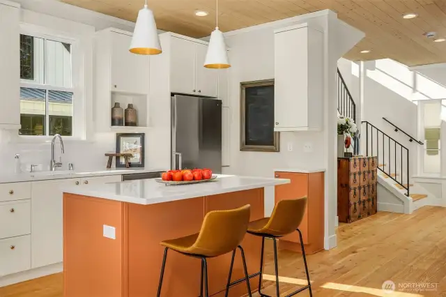The luxurious cooks kitchen features a large, deep Kohler sink, quartz countertops and warm color accents.