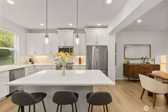 a sleek kitchen w/quartz counters, glass tile backsplashes, & top-ranked SS appliances.