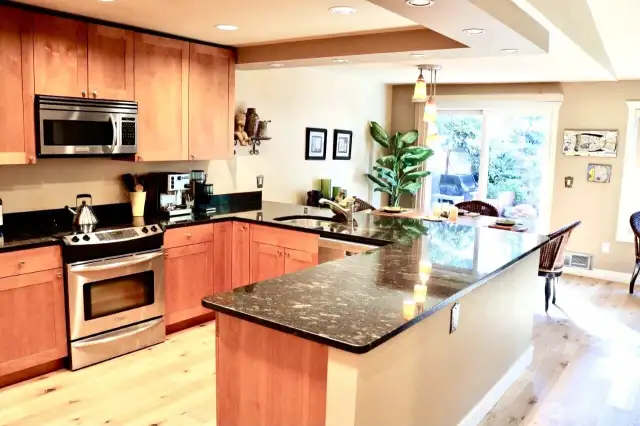 Stylish and functional, the kitchen is a true centerpiece of the home, perfect for both everyday living and entertaining. Featuring solid wood cabinetry, gleaming black granite countertops, and stainless-steel appliances