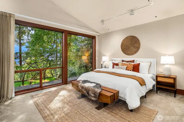 Tranquil, private, and light-filled, the main-floor primary suite features filtered lake views and a blooming dogwood that brings seasonal beauty each spring.