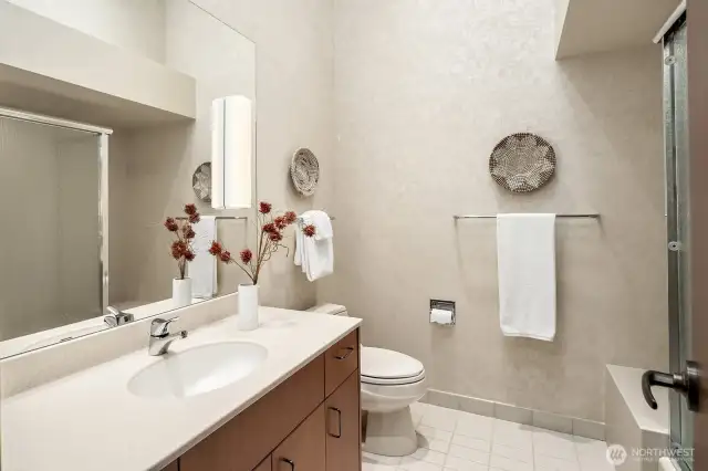 The en suite bathroom for bedroom #3 is filled with natural light from a skylight and features a spacious vanity, soaking tub, and walk-in shower.