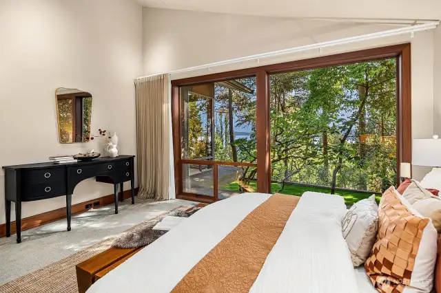 With vaulted ceilings, oversized windows, and serene lake views, the main-floor primary bedroom feels both spacious and retreat-like.