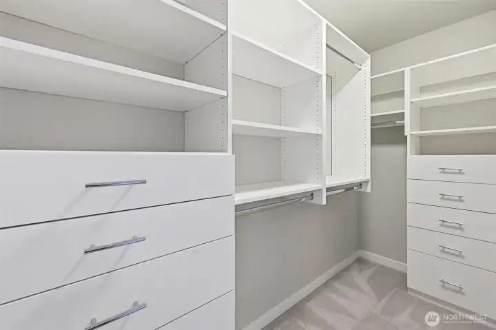 The primary bedroom walk-in closet features built-in drawers, shelves and places to hang clothes.