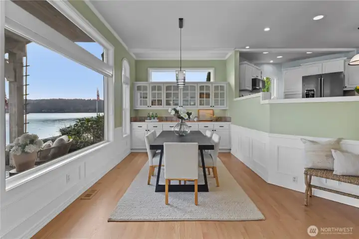 Light-filled dining area with built-in cabinetry and expansive windows showcasing beautiful waterfront views.
