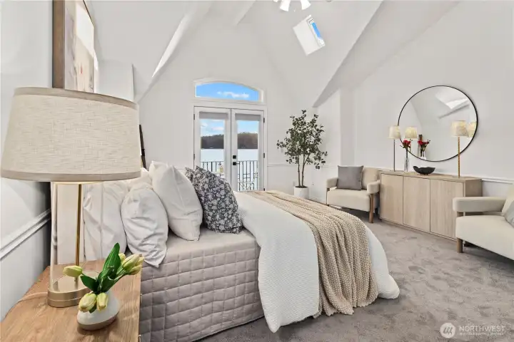 Serene primary suite with vaulted ceilings, abundant natural light, and direct access to a private balcony overlooking the waterfront.