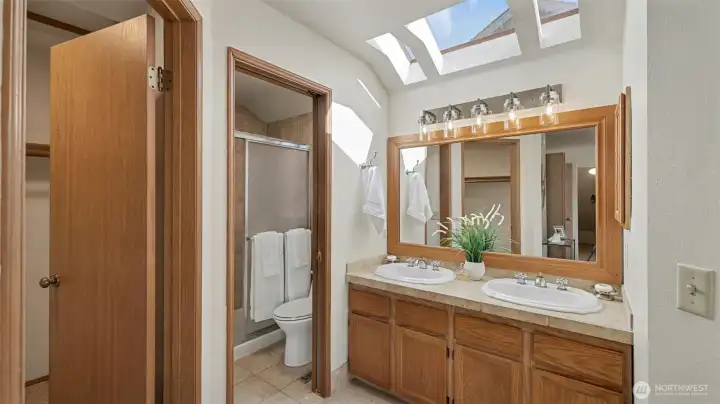 The primary 3/4 bath has tile floors, 2 vanities and skylights.