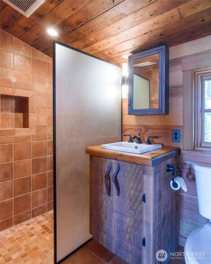 3/4 bath in main cabin has artistic custom cabinet, tile shower and heated floors