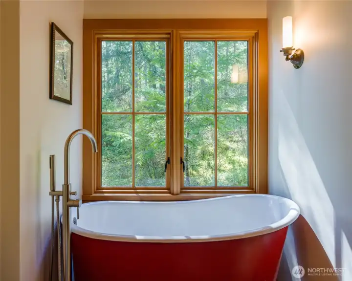 Soak in the luxurious cast iron tub with views out the window of the mossy hillside.