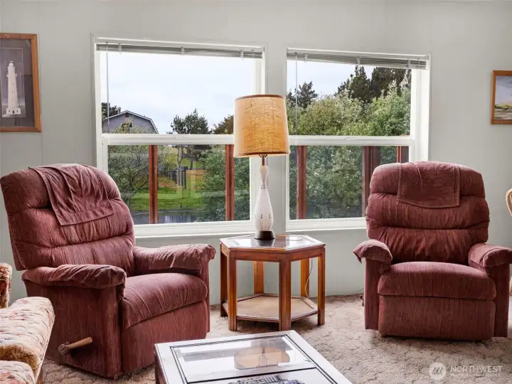Living room seating area with large picture window overlooking the property.