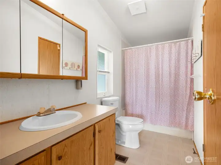 Primary bathroom with vanity storage and full tub/shower combination.