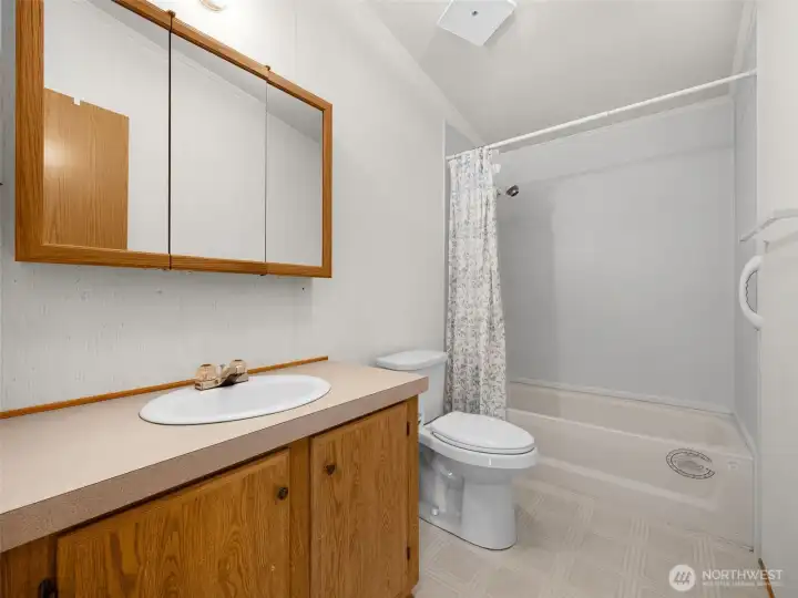 Second bathroom with oversized vanity and tub/shower combination.