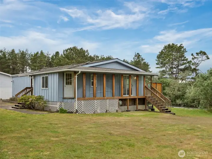 side exterior of the home showcasing the spacious deck, yard, and canal-side setting.