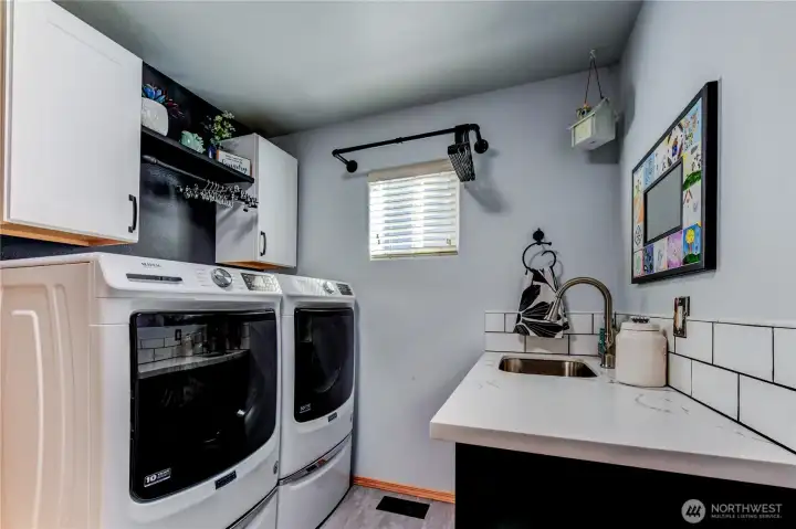 large laundry off garge with folding table, sink, and cabinets