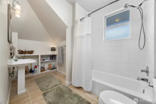 The full bath is large and has ceramic tile floors and a pedestal sink.