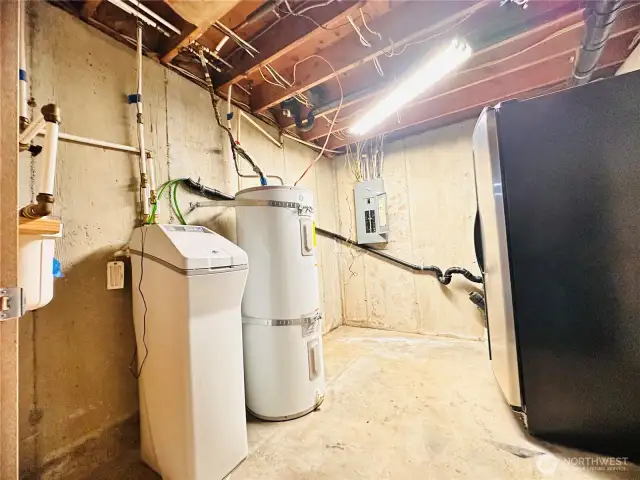 utility room with water heater, extra refrigerator that stays and water filtration system for home.