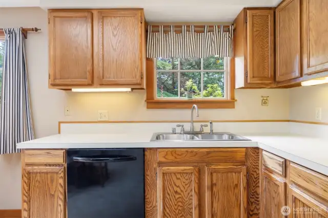 The window above the kitchen sink looks out to the driveway and the trees beyond.