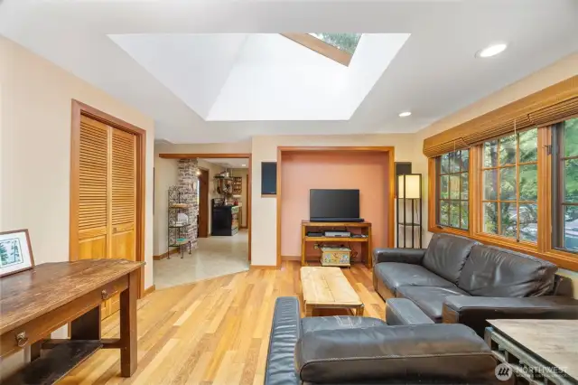 The family room is beyond the kitchen and has a large pantry/closet to the left. This room also looks out toward the driveway and the large trees beyond.
