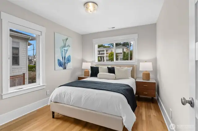 Main-level bedroom features large windows, a full closet, and gleaming hardwood floors—bright, comfortable, and versatile.