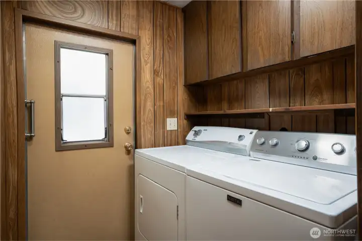 Dedicated laundry area with washer and dryer included, offering everyday convenience and functionality. Additional shelving and workspace provide practical storage and organization.
