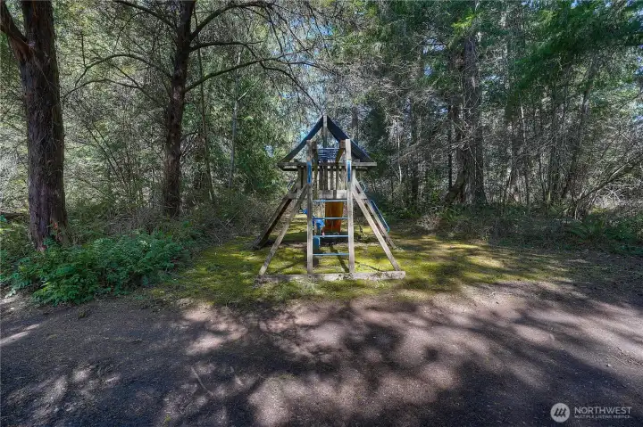 Private outdoor play area surrounded by mature trees, creating a peaceful and shaded setting. Perfect for enjoying the outdoors while embracing the natural beauty of the property.