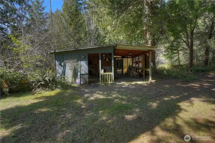 Charming outdoor retreat space perfect for family gatherings and entertaining. Covered area provides a comfortable setting to relax, cook, and enjoy the peaceful, wooded surroundings.