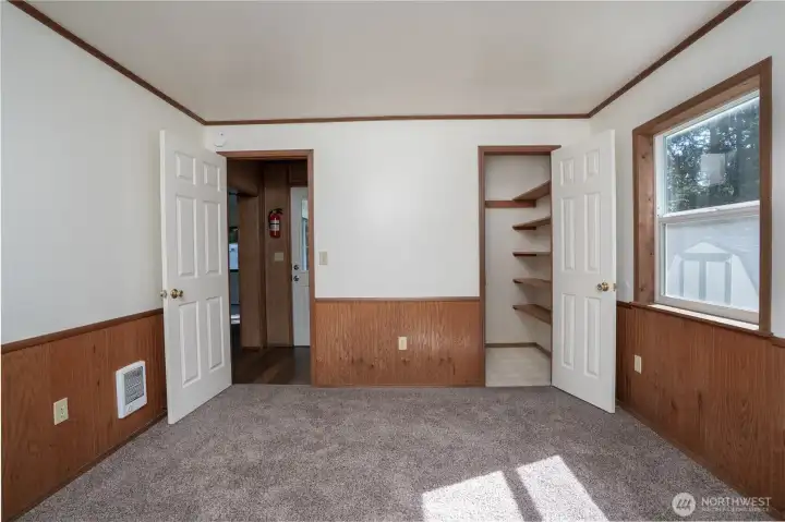 Comfortable bedroom featuring natural light and a spacious closet with built-in shelving for added storage. Functional layout provides flexibility for everyday living or guest use.