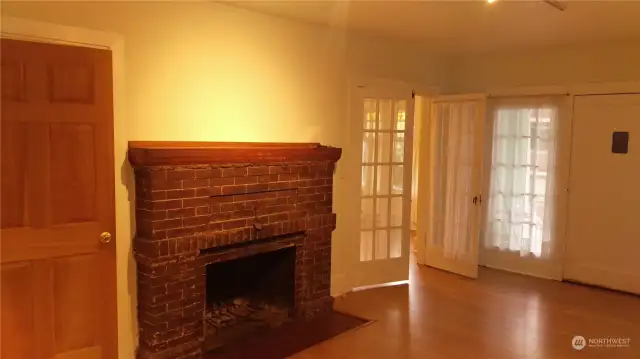 There is a brick fireplace in the living room of Apartment 1. The front door (on the right) opens to the covered porch.