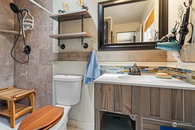 Custom tiled walk-in shower with floating corner shelf.
