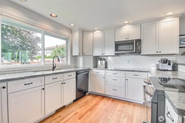 Trendy Chef's kitchen with stainless steel GE cafe appliances, including a smooth-top range and built-in microwave, enhance both style and convenience.
