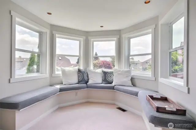 Reading nook framed by a stunning row of windows, this space offers panoramic views and abundant natural light.
