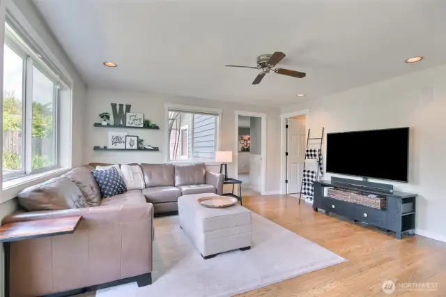 Recessed lighting and warm-toned hardwood floors add to the family room's welcoming ambiance.