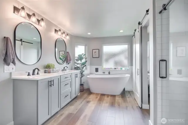 Dual vanities with modern matte black fixtures and elegant lighting flank the custom cabinetry.