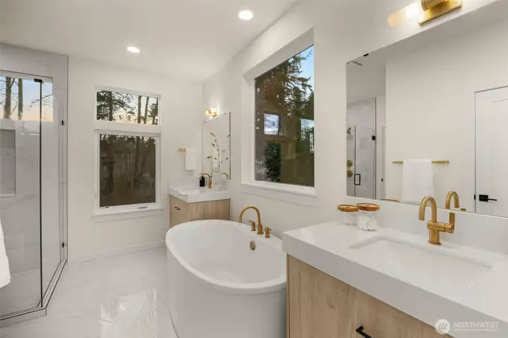 A chic spa-inspired luxurious bathroom, which includes a large glass-enclosed walk-in shower, and soaking tub.