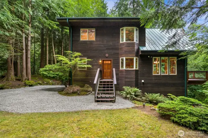 Nestled among towering evergreens, this custom home welcomes you with timeless architecture, a metal roof, and a peaceful setting that feels worlds away from the everyday.