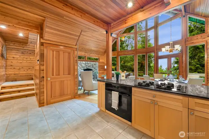 The kitchen flows seamlessly into the great room, where soaring cedar ceilings, expansive windows, and natural light create an inviting space for gathering.