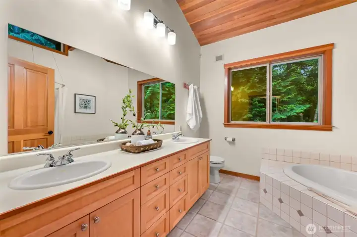 A spacious double vanity provides plenty of room for busy mornings, while large windows bring natural light and tranquil woodland views into the bathroom.