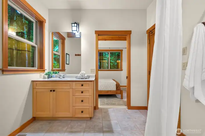 A spacious vanity, abundant natural light, and warm wood finishes create a comfortable and inviting primary bath.