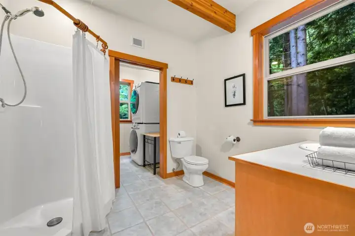The ensuite guest bath features a walk-in shower and connects directly to the adjacent laundry area for added functionality.