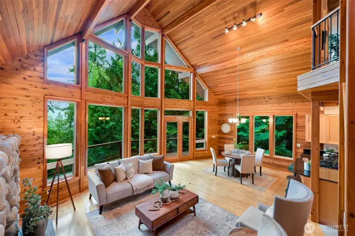A dramatic wall of windows creates a stunning focal point, offering an ever-changing backdrop of towering evergreens and glimpses of the surrounding landscape.