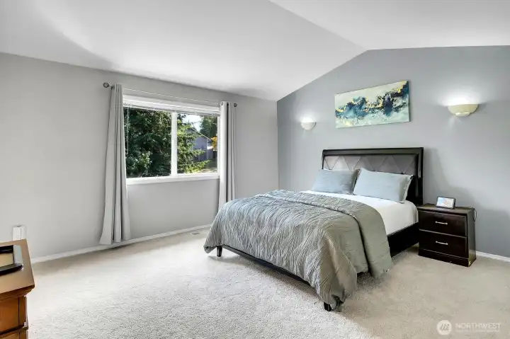 Spacious primary suite featuring vaulted ceilings, large windows, and room for a sitting area. Spacious primary suite featuring vaulted ceilings, large windows, and room for a sitting area.