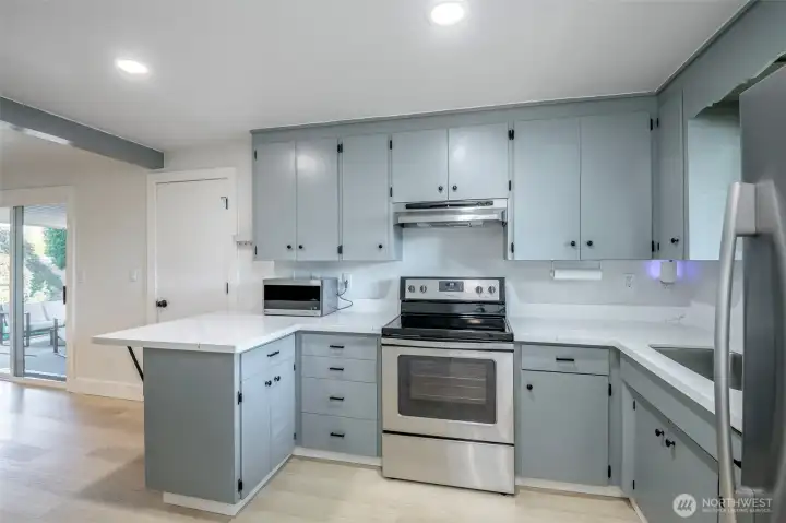 Beautifully remodeled kitchen with Quartz Countertops. Dining room off to the left of this photo with sliding glass door access to covered concrete patio. Dining bar with space for bar stools. Appliances included.