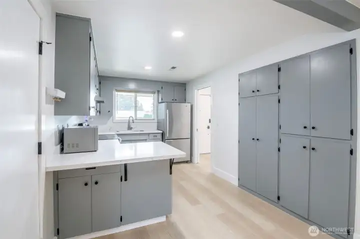 Tons of cabinets in this beautifully remodeled kitchen.  New appliances (convey) & Quartz Countertops. This open concept connects to dining room & sliding glass door access to patio.  On the left of photo is passage door to laundry area& garage.