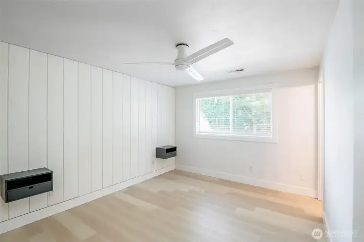 Primary bedroom (1 of 3 bedrooms). Separate 1/2 bathroom connected to this ensuite. New lighted ceiling fan.  Floating nightstands mounted to wall.