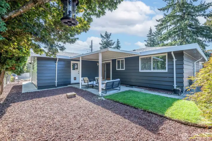 Photo from NE Side of property looking at covered patio & access to kitchen or passage door to garage.  Clear pathways to easily access all sides of the home.